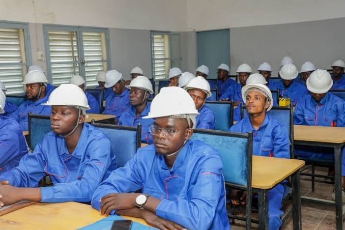 Apprenants en tenue bleue et casque de chantier dans un atelier de formation